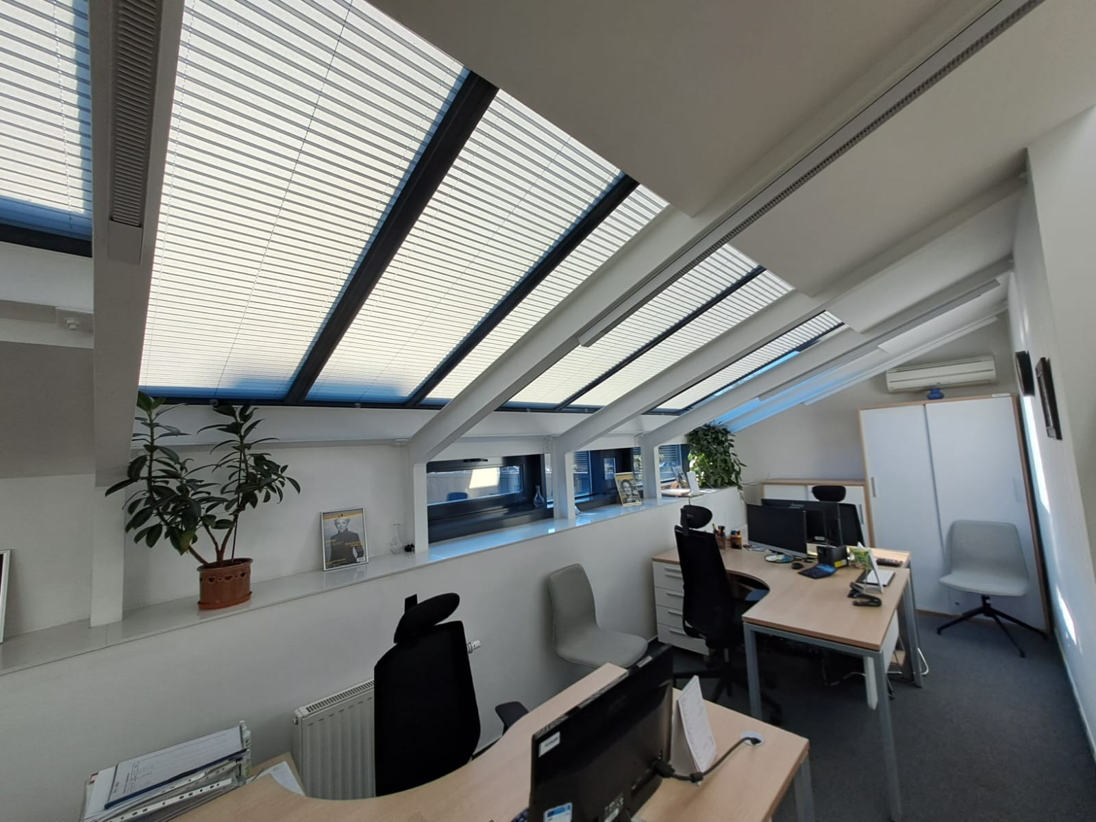 Zdjęcie ukazuje nowoczesne plisy dachowe zainstalowane w oknie połaciowym łódzkiego mieszkania. Te stylowe osłony okienne nie tylko estetycznie komponują się z wnętrzem, ale również zapewniają doskonałą ochronę przed nadmiernym nasłonecznieniem, zwiększając komfort użytkowania pomieszczenia.
